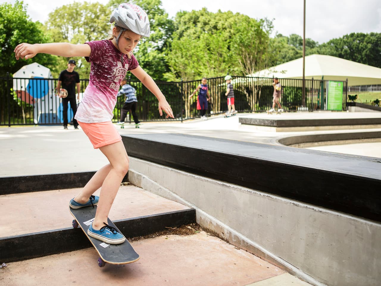 A girl skates down stairs at skatepark.