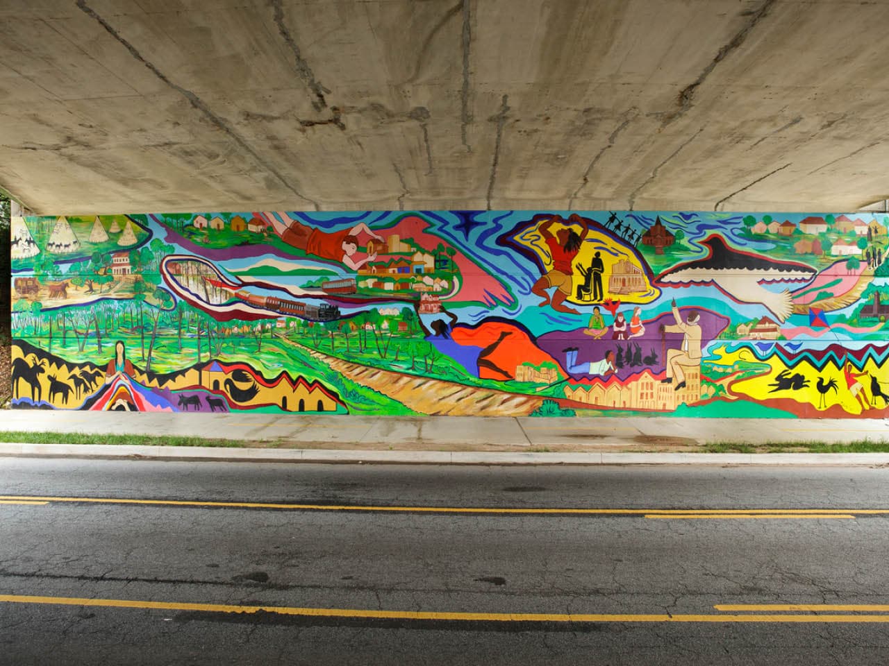 The mural "West End Remembers" by Malaika Favorite covers the length of a bridge abutment under Lawton Street.