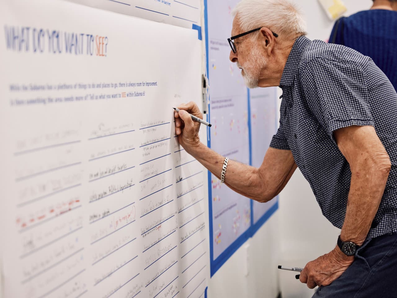 An older man writes what he wants to see on the Atlanta Beltline on a large poster.