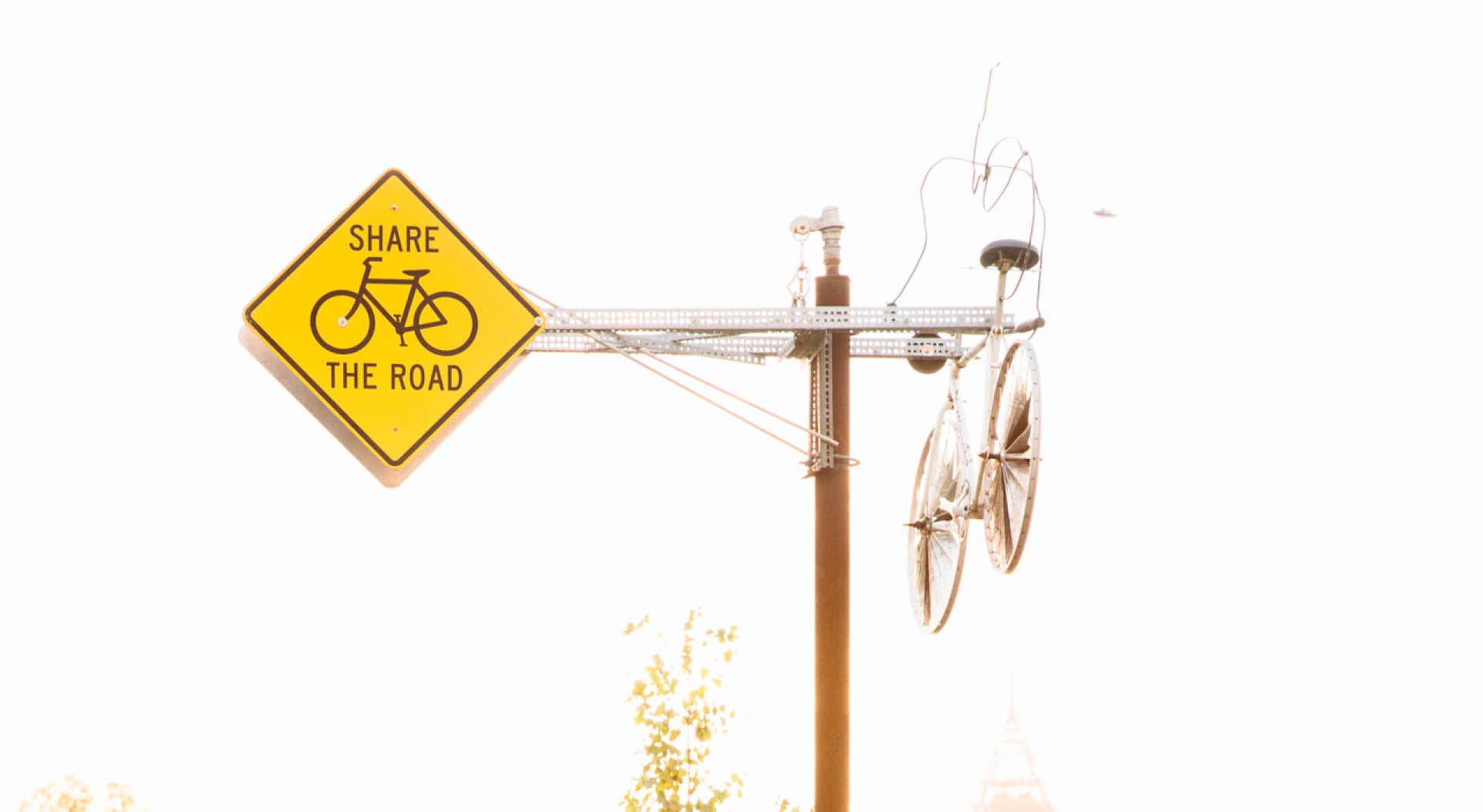 Sculpture made out of bicycle parts on a pole with "Share the Road" sign. (Photo Credit: Erin Sintos)
