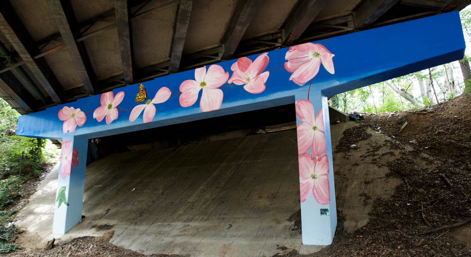 A mural of huge dogwood blossoms by artist Julie McKevitt is painted under a bridge. (Photo Credit: Christopher T. Martin)