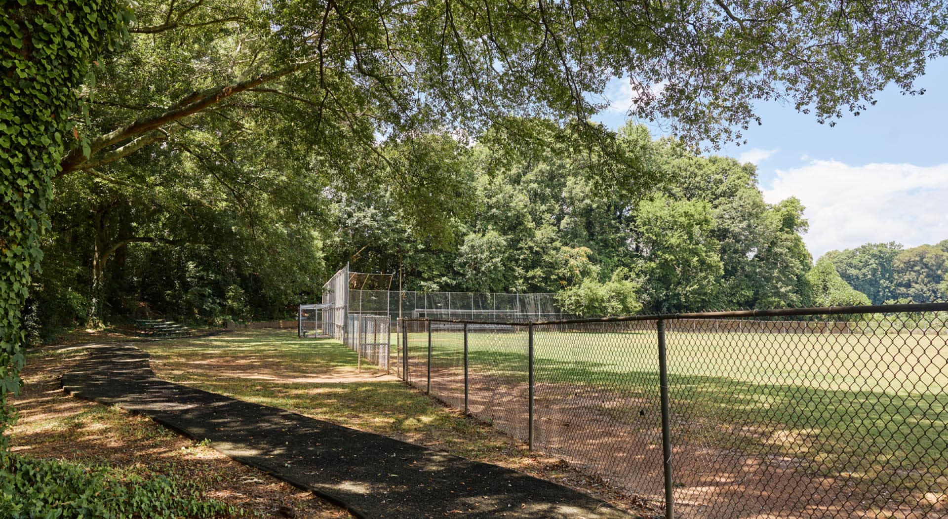 The baseball field in Arthur Langford, Jr. Park with a paved paths and bleachers in the shade. (Photo Credit: Erin Sintos)