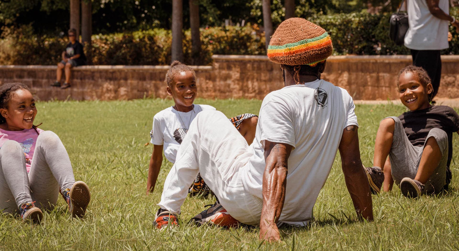 A man teaches children in the grass at the Juneteenth Festival in 2022 hosted by MuseSalon Collaborative. (Photo Credit: Timberhouse Films)