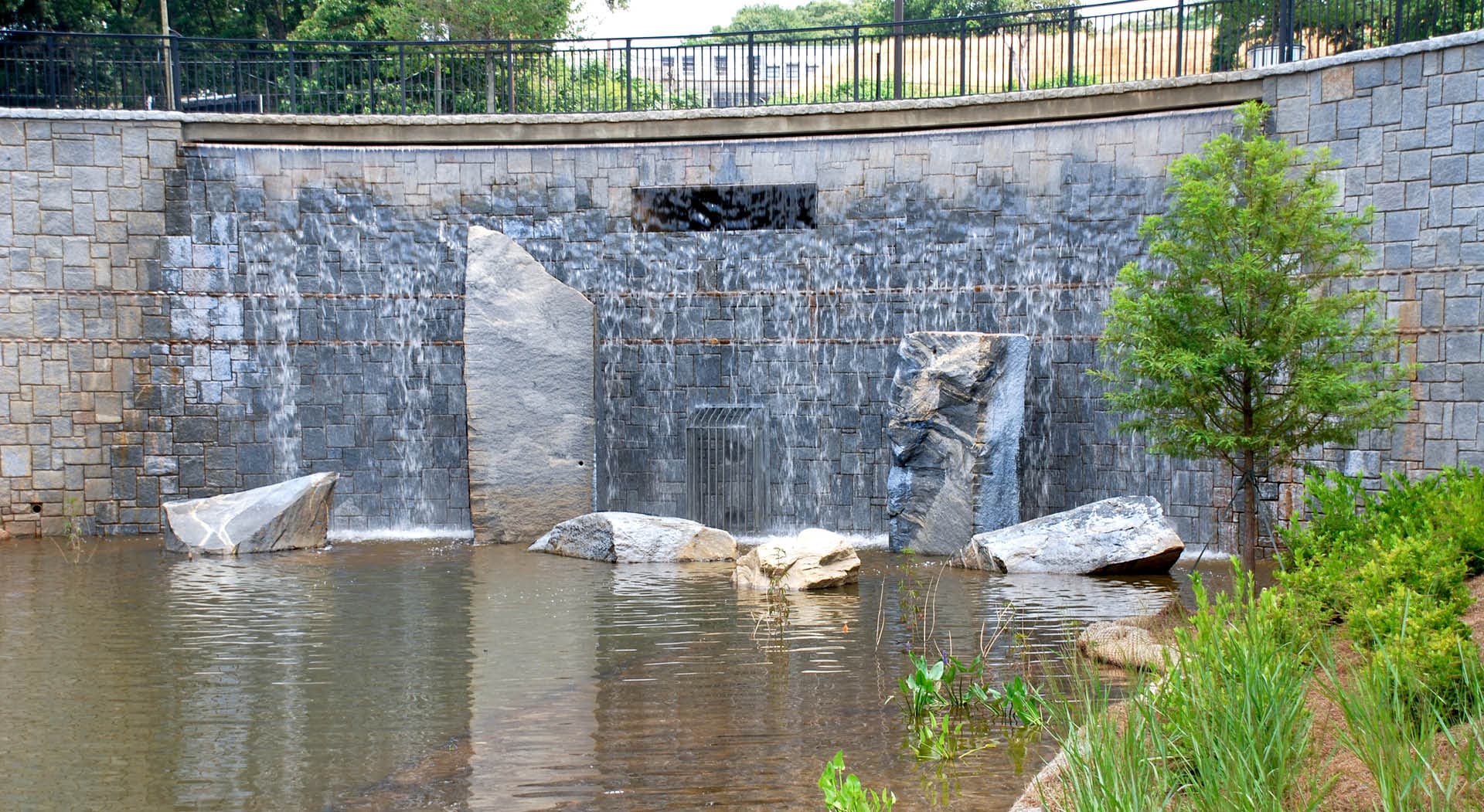 Granite wall with waterfall and sculptural boulders.