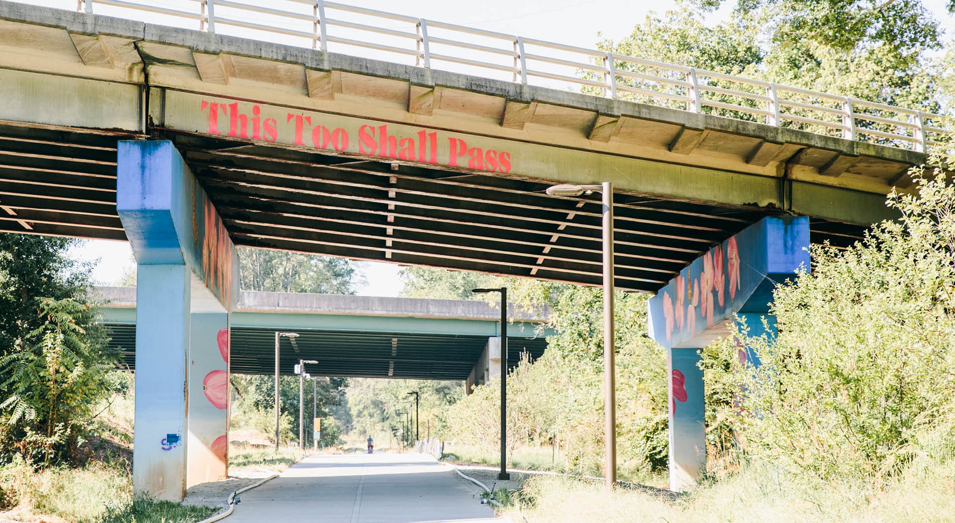 The Beltline's Westside Trail passes under a bridge with its supports painted with huge dogwood blossoms. (Photo Credit: Erin Sintos)
