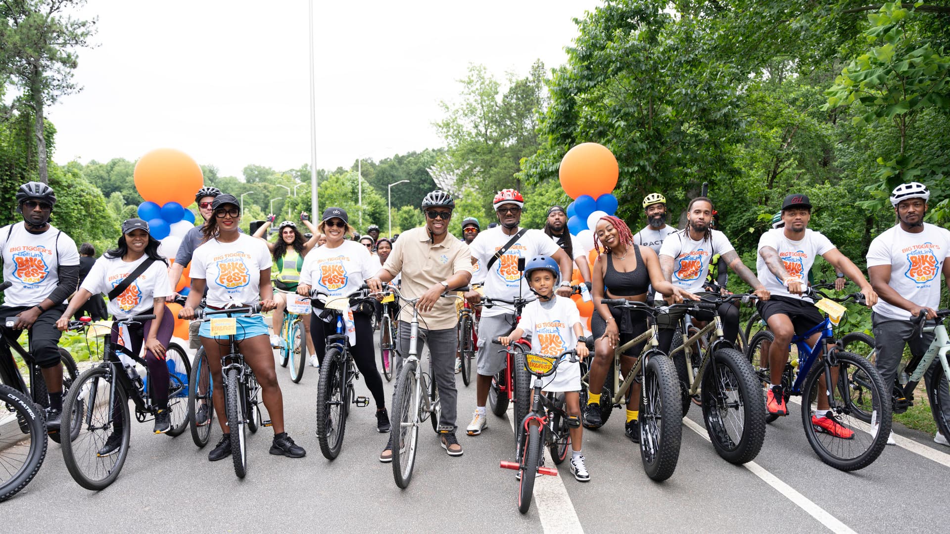 A group of people stand on their bikes smiling and ready to ride.