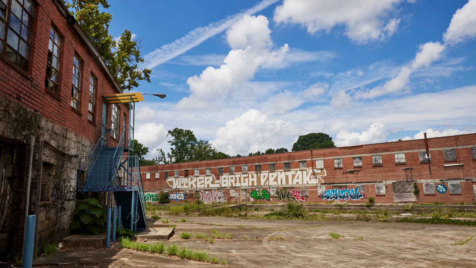 Two abandoned warehouse buildings are shown covered in colorful graffiti.