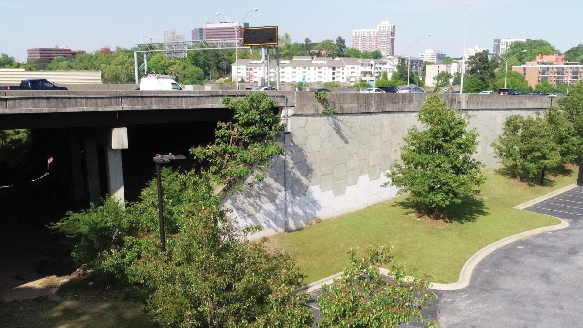 A photo shows cars going over an interstate overpass with a parking lot below.