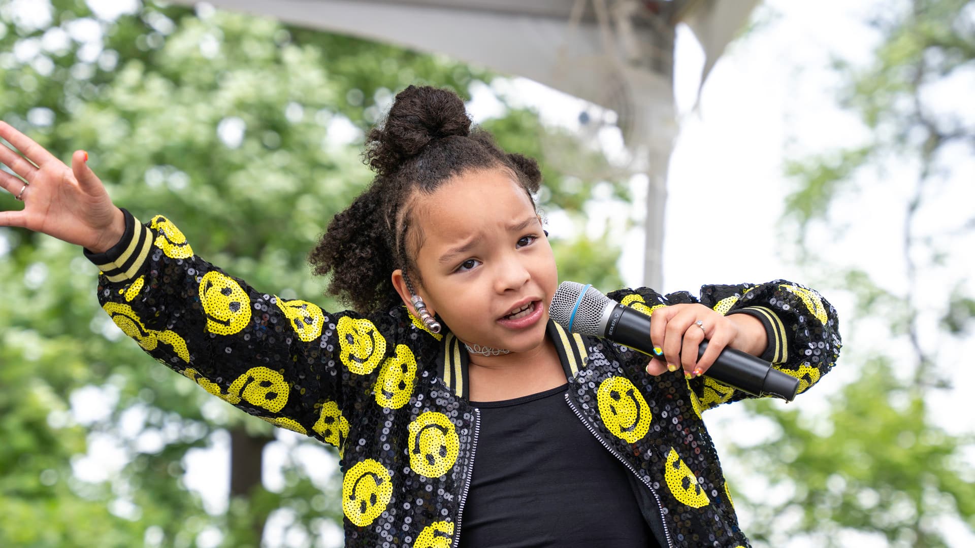 A girl performs in front of a crowd with a microphone.