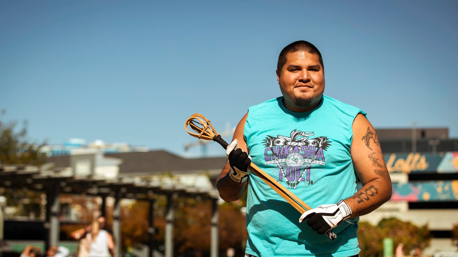 A person stands, holding a toli stick and smiling for the camera.