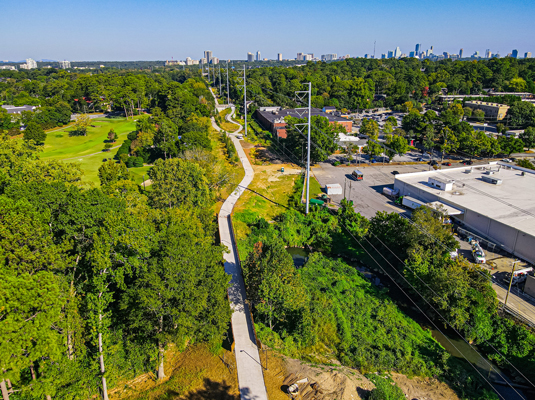 View of Northeast Trail – Segment 2 looking north with Ansley Mall to the right, Ansley Golf Course to the left, and the bridge over Clear Creek in the foreground. Photo by LoKnows Drones.