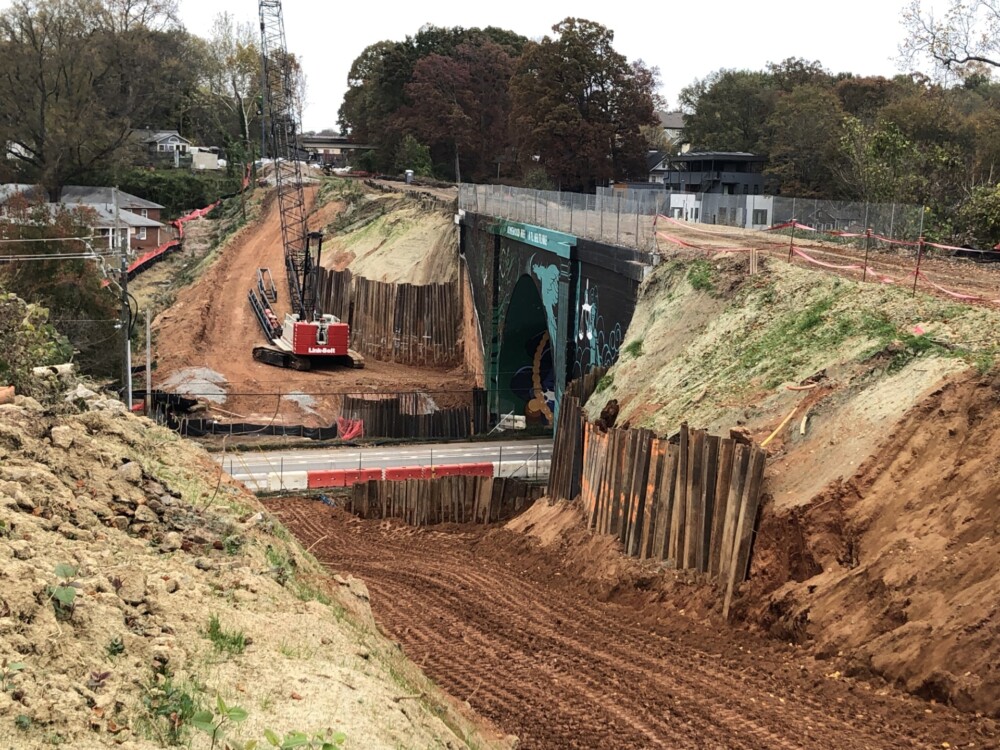 A new pedestrian bridge is under construction that will run parallel to the historic bridge at Ormewood Ave SE. Shoring to retain soil is place, with footing excavation, formwork, and rebar placement in progress. November 17, 2023. Photo by Kerri Parker.